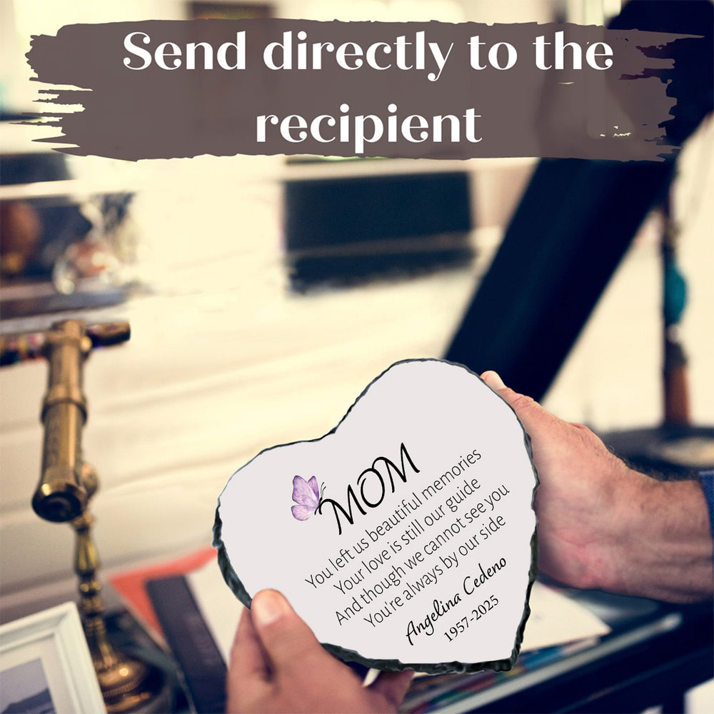 Person holding a personalized stone with a message for 'MOM' in a blurred indoor setting.
