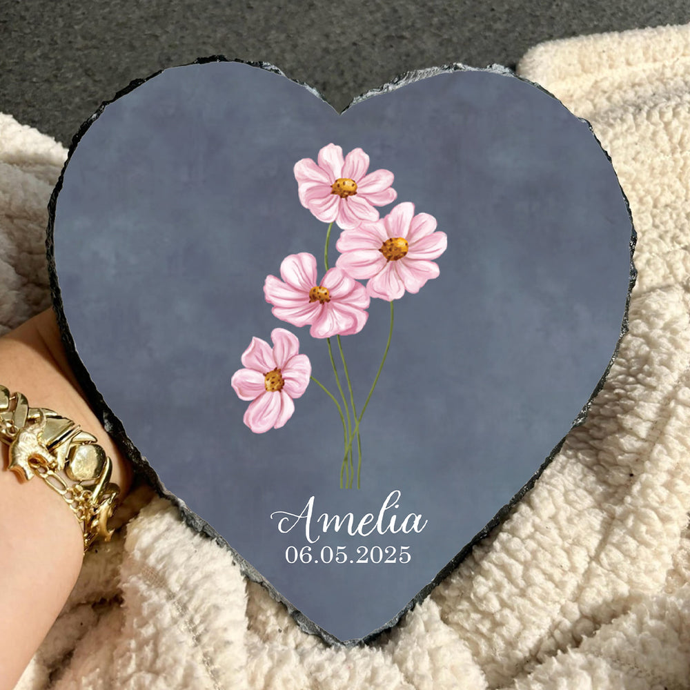Heart-shaped slate with pink flowers and 'Amelia' and a date on a textured surface