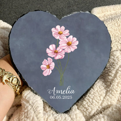 Heart-shaped slate with pink flowers and 'Amelia' and a date on a textured surface