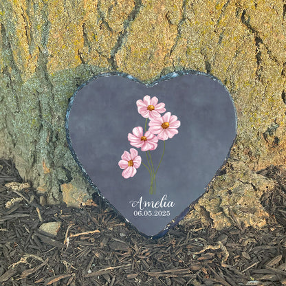 Personalized baby girl memorial stone at sunlit tree base. Features pink cosmos flowers. Customized with name Amelia. Hopeful sympathy gift.