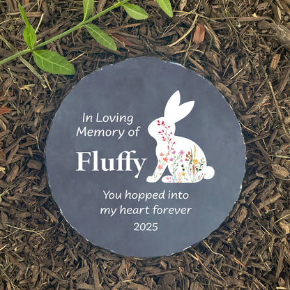 Personalized floral bunny memorial stone, round shape, on dark mulch. Customized with name Fluffy. Sympathy gift for loss of rabbit.